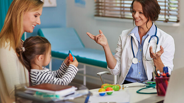 A mother holding a child whilst a GP speaks to them