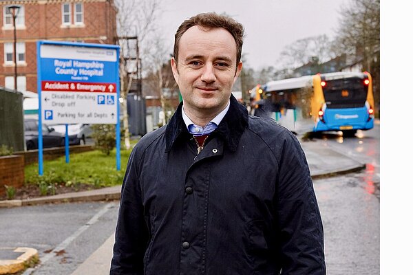 Danny Chambers standing in front of the Royal Hampshire County Hospital in Winchester. A sign for the A&E is in the background.